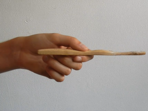 Main tenant une brosse à dents en bambou dont les poils ont été retirés